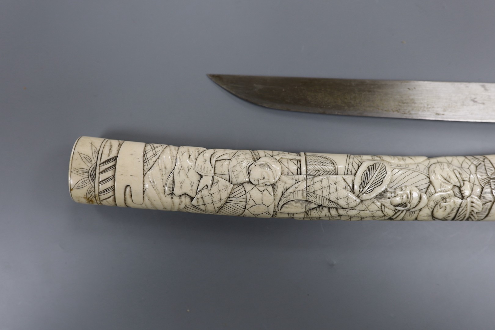 A Japanese carved bone tanto, c.1900, carved with numerous figures, overall 36cm